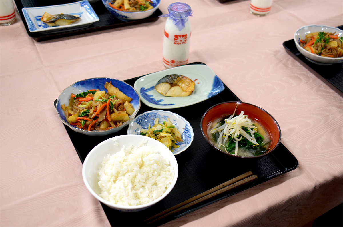 メニューは、通常の和食給食にプラスして、温かいみそ汁とデザートが付き、「ご飯、みそ汁、サバの文化干し、じゃがいものきんぴら煮、おひたし、白玉だんご、果物（いちご・オレンジ）」といった、一汁三菜プラスαの“和食膳”。