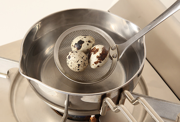 冷蔵庫から出したてのうずらの卵を沸騰した湯に入れ、2分30秒程茹でる。茹で上がったら冷水に取って殻をむき、半分に切る