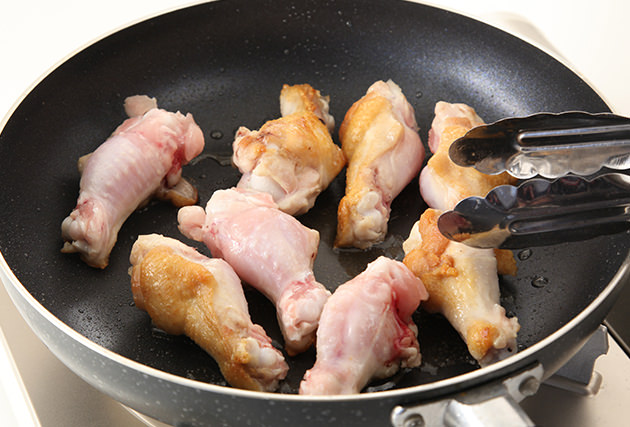 フライパンにオリーブオイル(大さじ１)を熱し、水気を拭き取った(１)の鶏手羽元を焼く。表面にカリッと焼き色がついたら裏返して両面に焼き色をつける。